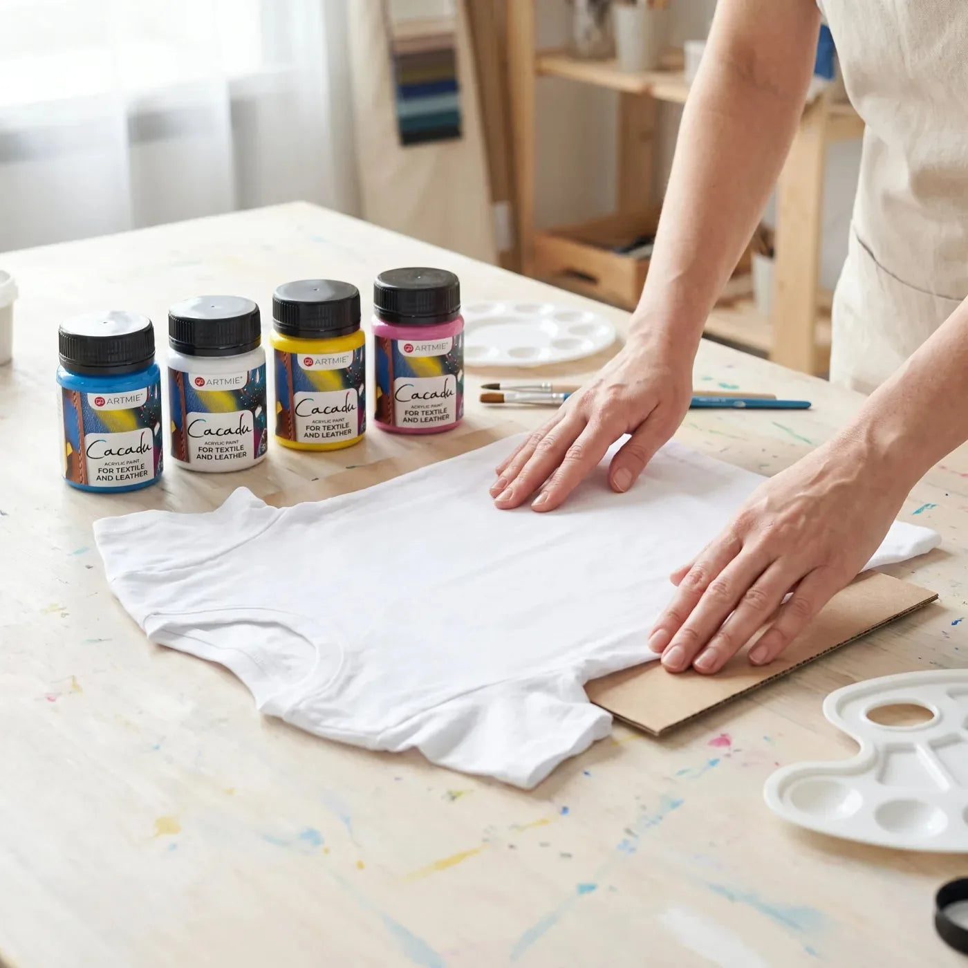 Smoothing a white T-shirt with cardboard inside, next to Cacadu fabric paint