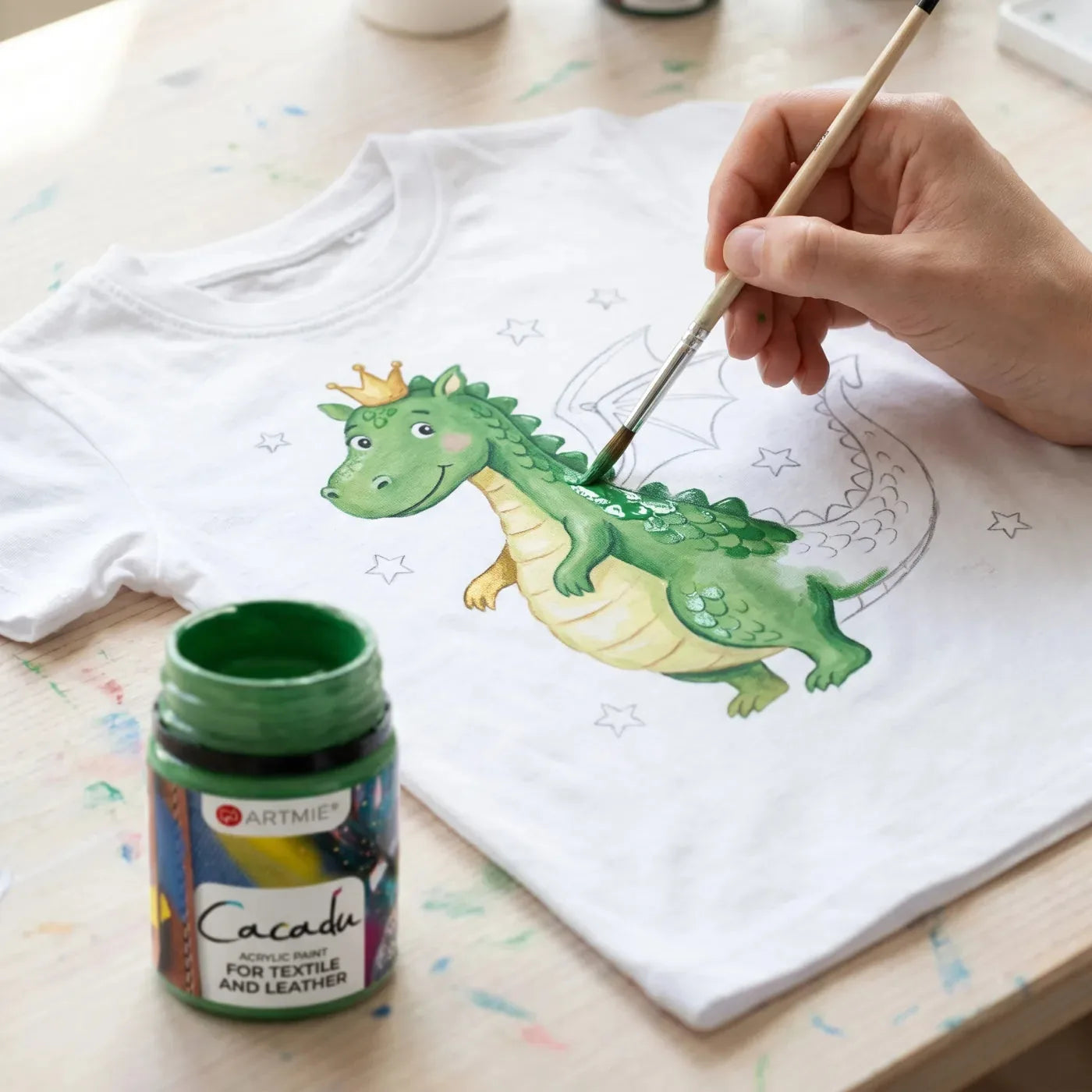 Detail of a green dragon being painted on a T-shirt with Cacadu paint