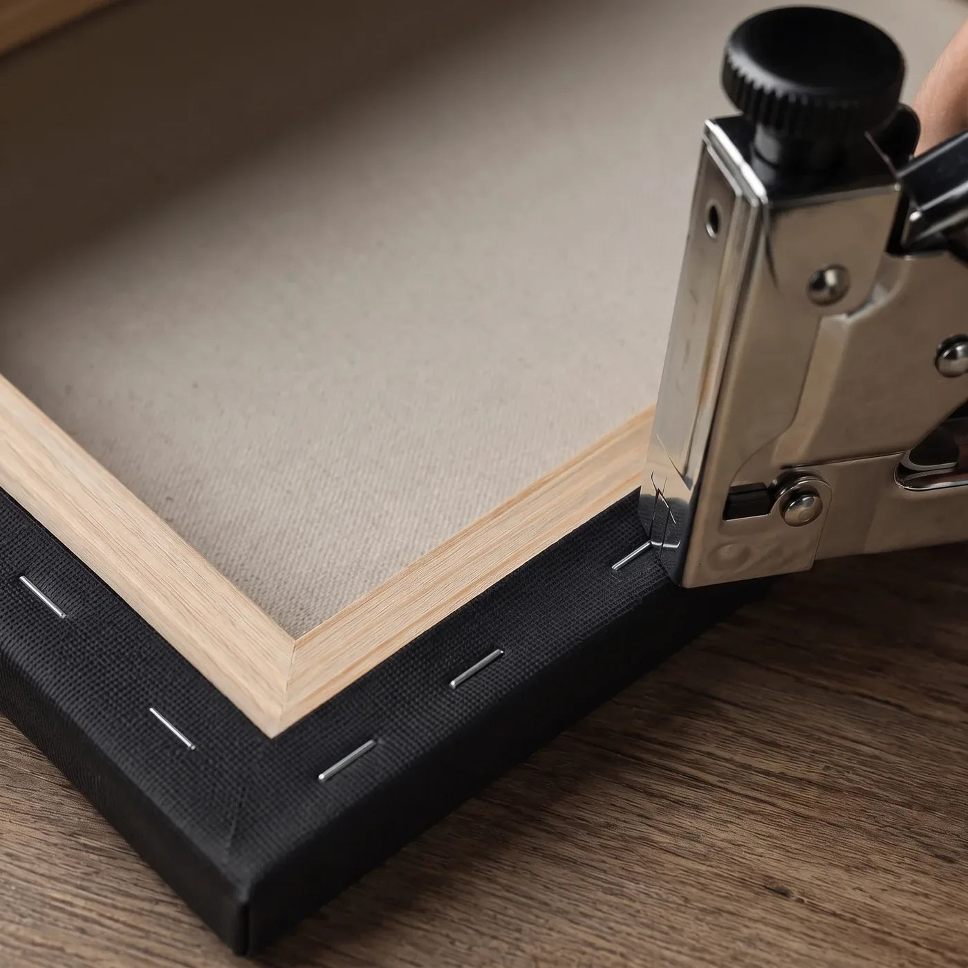 Stretching black canvas over a spruce stretcher bar and fastening it with staples