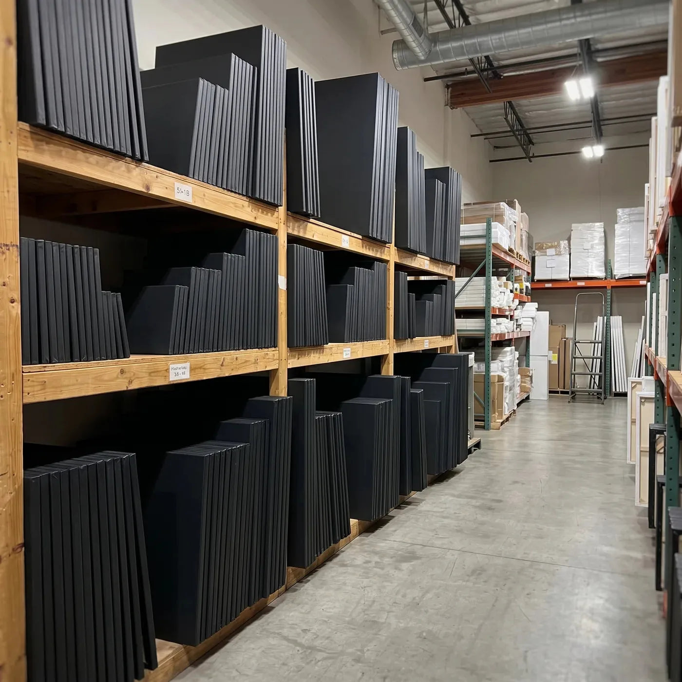 Finished black canvases standing side by side on a storage rack
