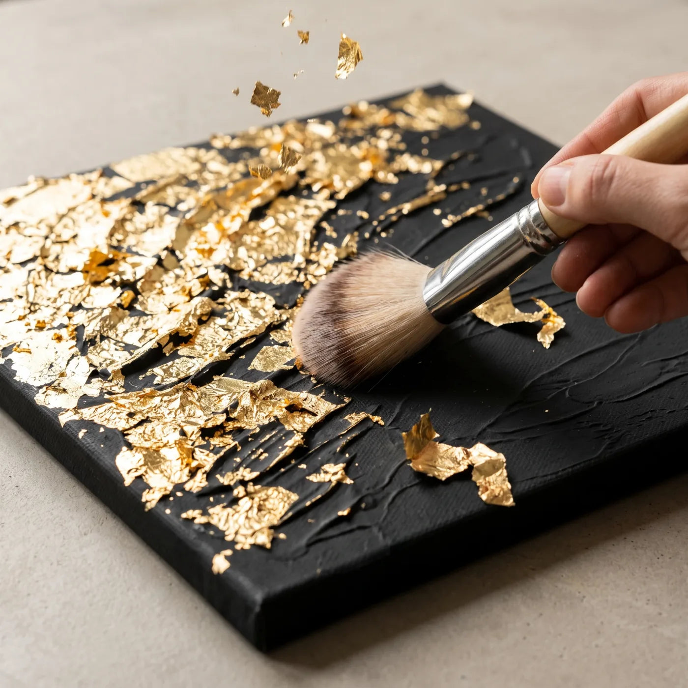 Brushing excess gold leaf off a gilded relief with a soft brush