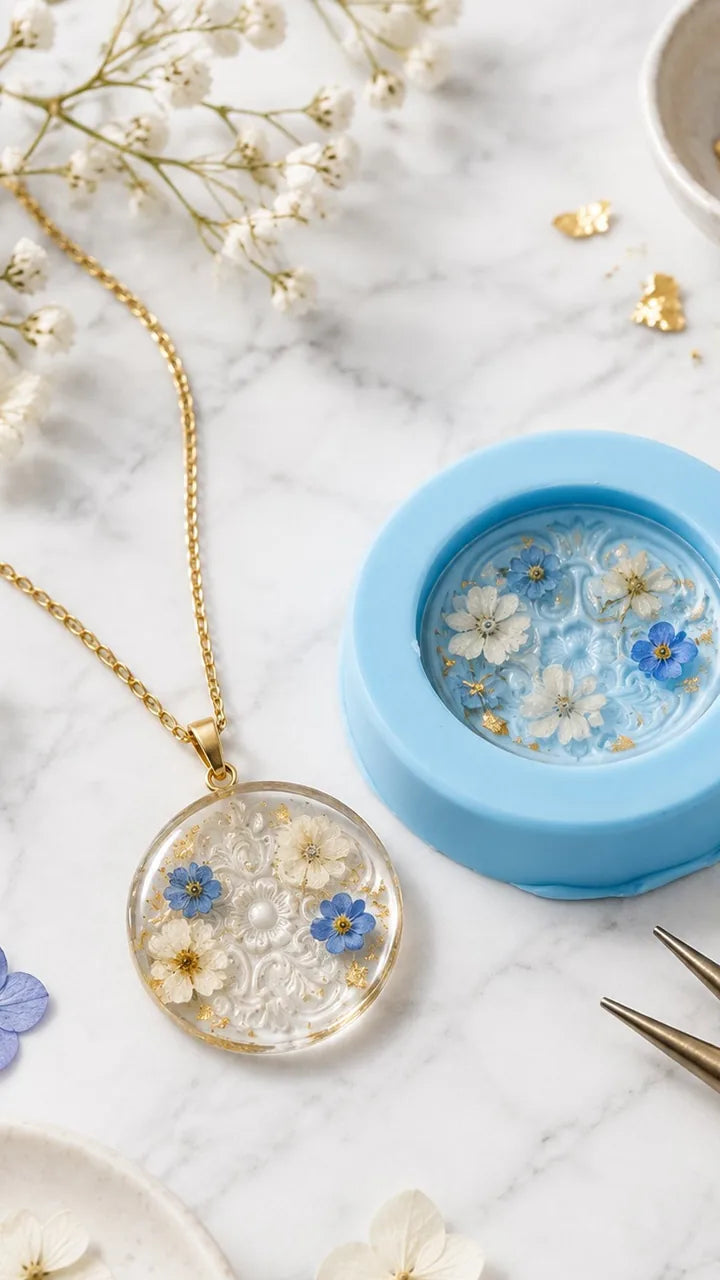 Blue silicone mold with resin and dried flowers beside a finished pendant on a gold chain